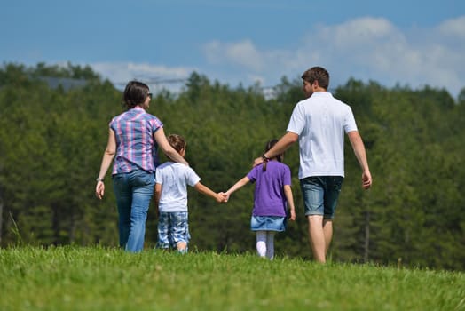 happy young family with their kids have fun and relax outdoors in nature with blue sky in background