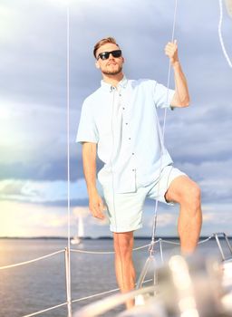 Relaxing man happily on the vacation sailboat yacht standing on a deck.