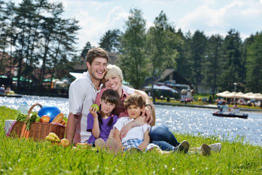 Happy young  family playing together with kids and eat healthy food  in a picnic outdoors