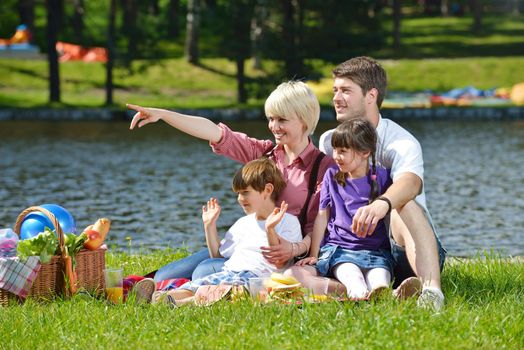 Happy young  family playing together with kids and eat healthy food  in a picnic outdoors