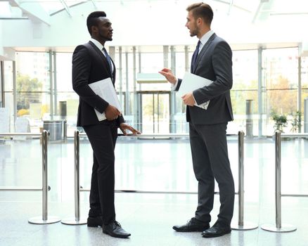 Two multinational young businessmen discussing business at meeting in office.