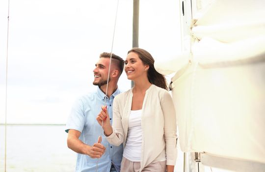 Attractive couple on a yacht enjoy bright sunny day on vacation.