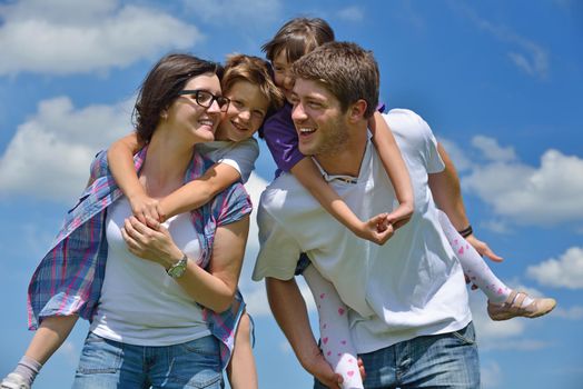 happy young family with their kids have fun and relax outdoors in nature with blue sky in background