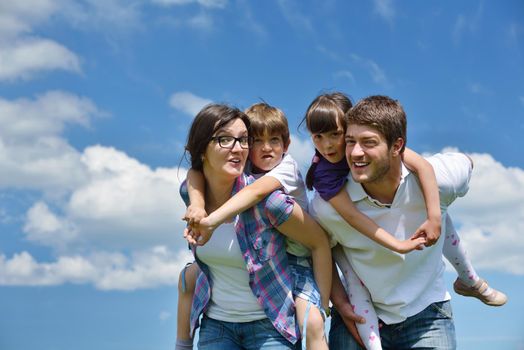 happy young family with their kids have fun and relax outdoors in nature with blue sky in background