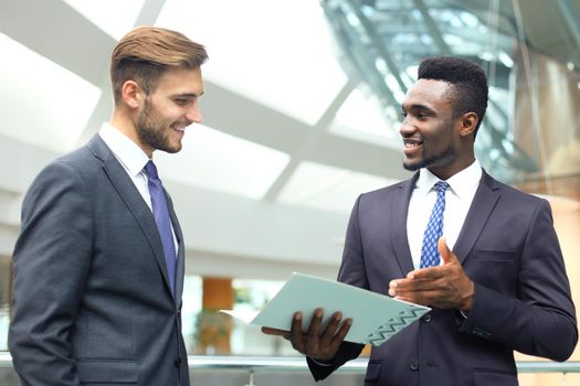 Two multinational young businessmen discussing business at meeting in office.