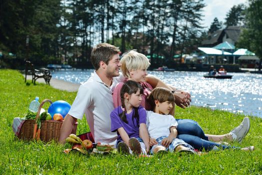 Happy young  family playing together with kids and eat healthy food  in a picnic outdoors