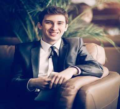 Relaxed businessman sitting in front of the Windows in office