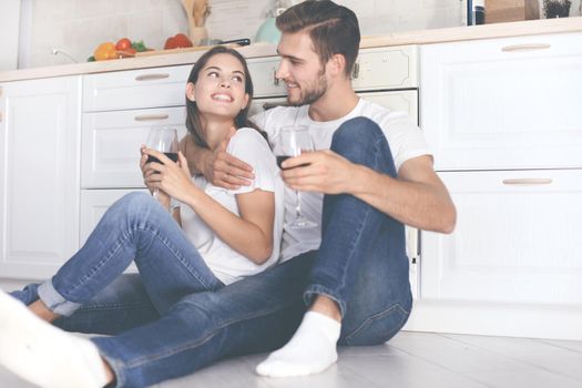 happy young couple sitting on floor in kitchen at home.