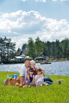 Happy young  family playing together with kids and eat healthy food  in a picnic outdoors