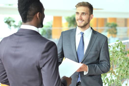 Two multinational young businessmen discussing business at meeting in office.