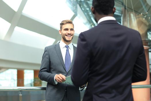 Two multinational young businessmen discussing business at meeting in office.