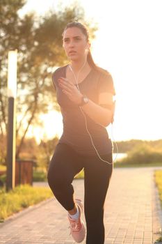 Young fitness attractive sporty girl runner in start position outdoor at sunset or sunrise in city