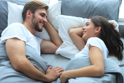 Cheerful couple awaking and looking at each other in bed.