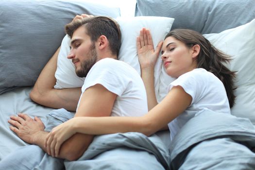 Happy couple sleeping in a comfortable bed at home.