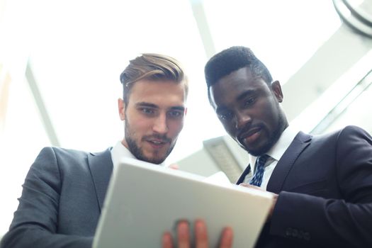 Two multinational young businessmen discussing business at meeting in office.