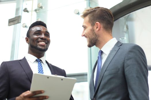 Two multinational young businessmen discussing business at meeting in office.