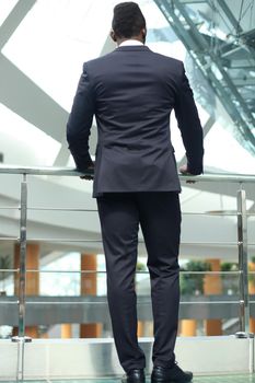 Rear view of African American businessman in suit looking forward, in office building.