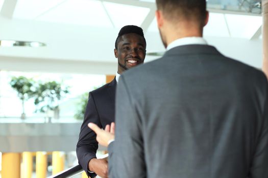 Two multinational young businessmen discussing business at meeting in office.