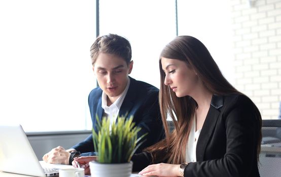 Business partners working together at office desk, they are using a laptop.