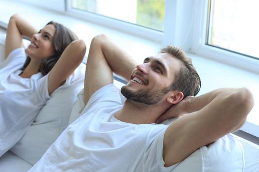 Smiling beautiful couple sitting on a sofa and dreaming about new home.