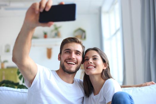 Young couple taking a selfie on couch at home in the living room.