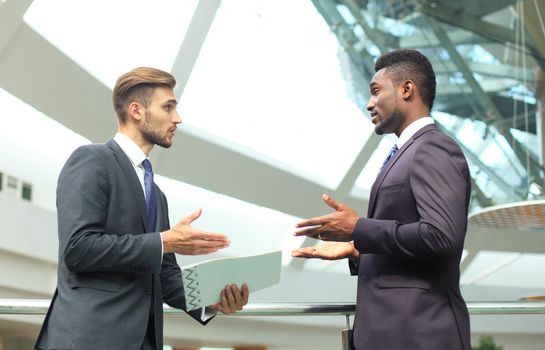 Two multinational young businessmen discussing business at meeting in office.