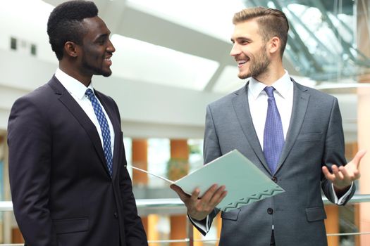 Two multinational young businessmen discussing business at meeting in office.