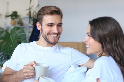 Cheerful young couple in the morning at home in the living room.