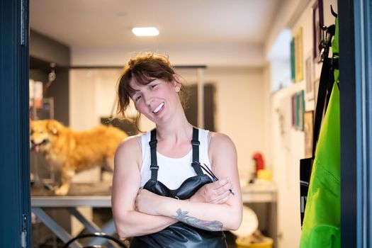 portrait of professional pet hairdresser hipster woman with tattoos while standing at the door of her beauty salon for animals