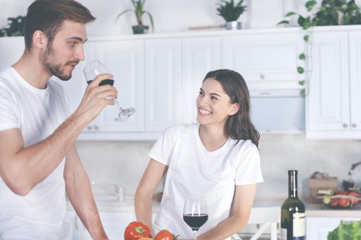 Pretty young woman drinking some wine at home in kitchen.