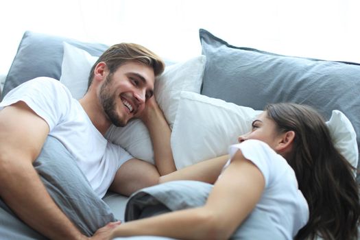 Cheerful couple awaking and looking at each other in bed.