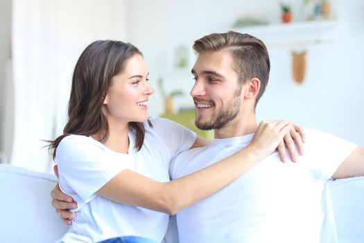 Happy young couple hugging and looking at each other at home interior.