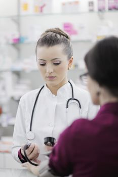 doctor checking blood pressure and heart rate in a hospital or in pharmacy with young female patient