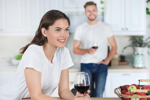 Pretty young woman drinking some wine at home in kitchen.