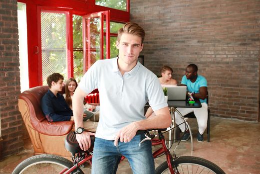 Young man sitting on a bicycle in a modern office
