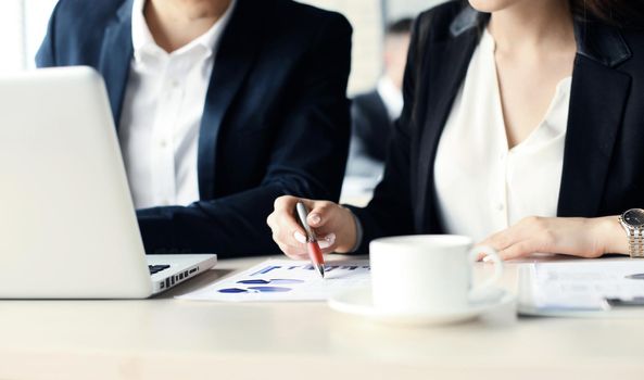 Business partners working together at office desk, they are using a laptop.