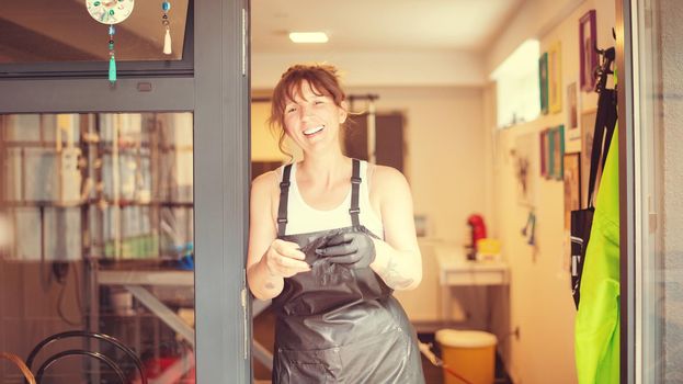 portrait of professional pet hairdresser hipster woman with tattoos while standing at the door of her beauty salon for animals