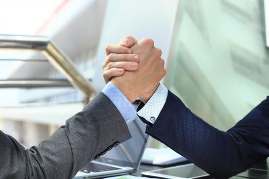 Two businessmen press hands each other on a forward background.