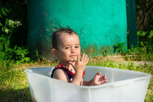 Little girl in a swimsuit playing and smiling sitting in the bath