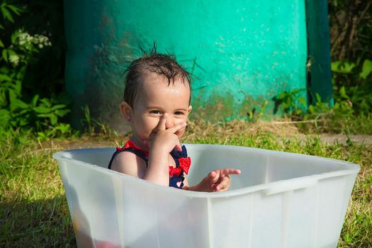 Little girl smiling on a hot day sitting in the bath
