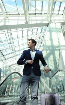 Businessman at the airport going down the escalator.