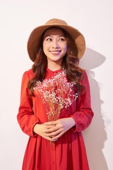 a lovely young woman in summer dress and straw hat posing while holding bouquet flowers