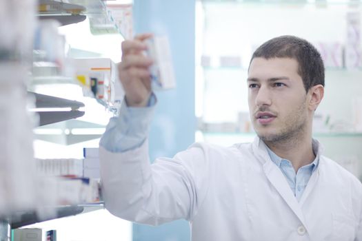 portrait of handsome young  pharmacist chemist man standing in pharmacy drugstore