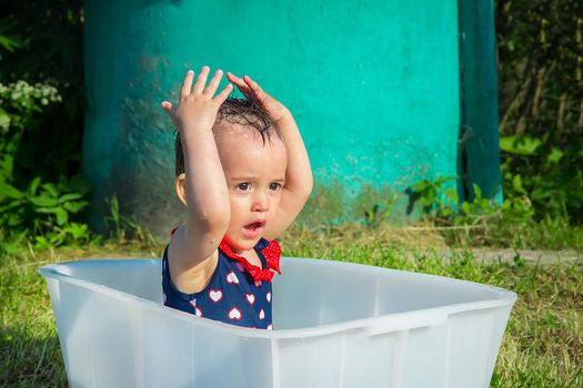 On a hot summer day, a year and a half girl washes her head on her own