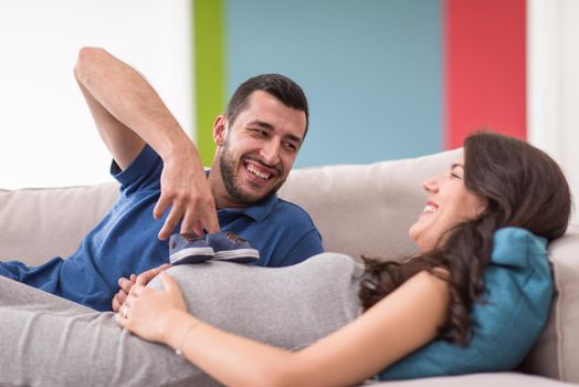 happy pregnant couple relaxing on sofa couch at home