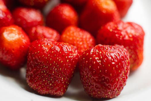 Macro stock photo of large organic sweet strawberries in sunlight. Strawberry texture in close-up. Seeds and dirt.