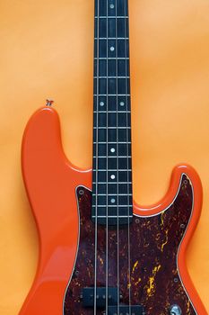orange electric bass guitar on orange background with copy space