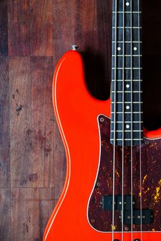 orange electric bass guitar on wood background with copy space