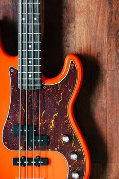 orange electric bass guitar on wood background with copy space