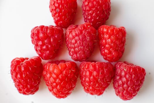 Stock photo close-up of juicy raspberries sorted on white background. Isolated on white background.